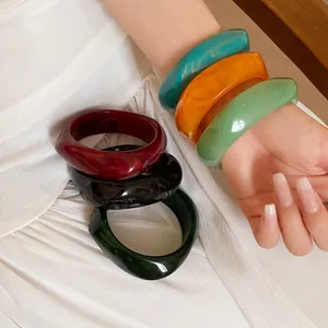 Detailed view of colorful marbled resin bangles showing vibrant textures and square spiral shape.