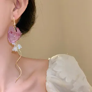 Close-up of elegant chiffon flower tassel earrings with zircons and pearls on model.
