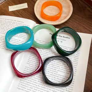 Detailed view of colorful vintage resin spiral square bangles on an open book background