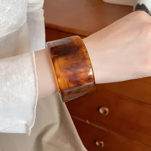 Detailed macro view of a vintage amber resin bangle with wood grain texture on a wrist