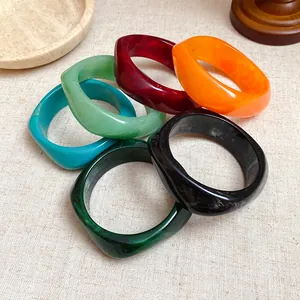 Macro view of vibrant geometric resin bangles featuring marbled textures in various colors