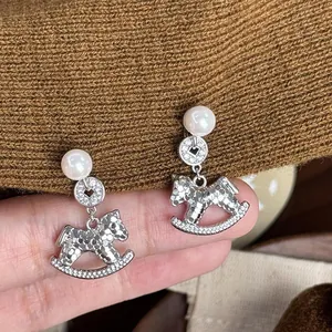 Elegant silver rocking horse drop earrings featuring white pearls and sparkling pavé stones