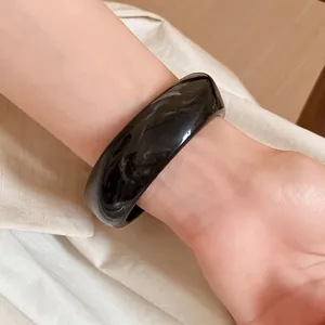 Detailed close-up view of a vintage black marbled resin square spiral bangle worn on a wrist