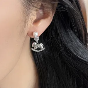 Elegant silver stud earrings with pearl and sparkling rocking horse charm for women