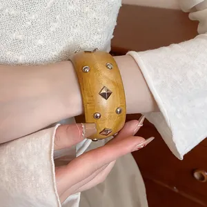 Close-up detail of retro wood grain bangle bracelet with silver metal studs on model wrist