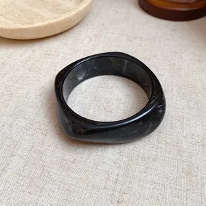 Detail view of black marbled resin square bangle with elegant white swirled patterns