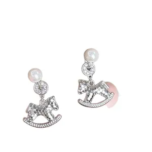 Elegant silver rocking horse earrings with pearls and pavé crystals on white background
