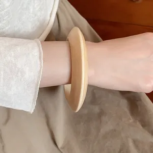 Close-up detail of a minimalist vintage wooden bangle featuring natural grain on wrist.