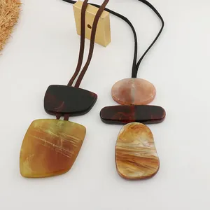Macro detail of marbled resin geometric pendants on long adjustable leather cord necklaces