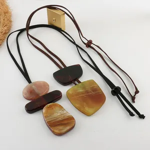 Detail view of long cord necklaces featuring amber and brown marbled resin geometric pendants.