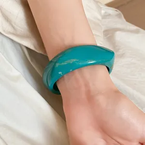 Close-up detail of a turquoise resin bangle with a unique twisted square geometric design.