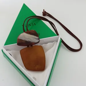 Close-up of large geometric resin pendant necklace with brown leather cord