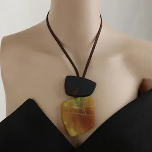 Detailed view of an oversized geometric resin pendant necklace on a brown cord