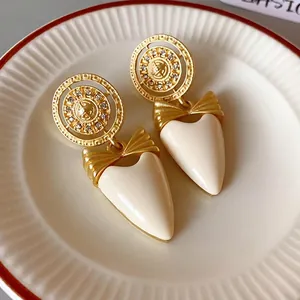 Vintage gold-tone bow earrings with white heart drop and rhinestone accents