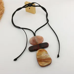 Detail view of oversized geometric resin pendant with marble pattern on black cord