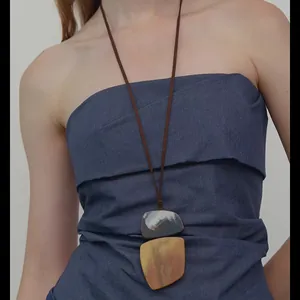 Detailed view of a resin geometric pendant necklace with marble dye on a brown leather cord.