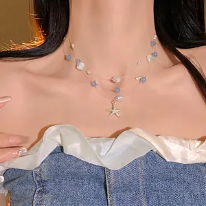 Layered beach style necklace with starfish, seashell, and pearl pendants on a model.