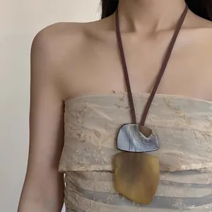 Close-up of geometric resin pendant necklace with marbled texture on brown cord