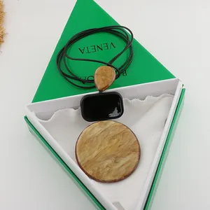 Detail view of geometric resin pendant necklace with marble pattern on a green gift box