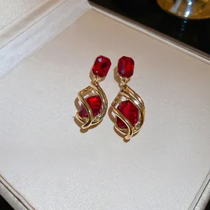 Close-up of vintage red gemstone earrings with gold-toned swirl design and elegant luster.