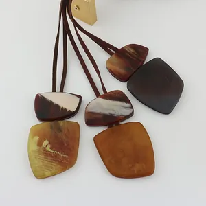 Close-up of marbled resin geometric pendants with dark brown leather cords on white background