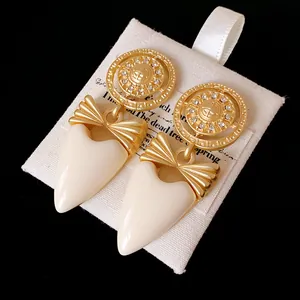 Detailed view of vintage gold bow heart earrings with rhinestones on a white pouch (81 chars)