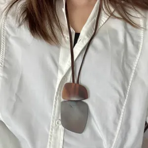Close-up of a geometric resin necklace with a brown and grey marbled ink-wash effect