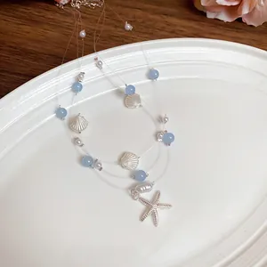Detail view of multi-layer starfish necklace with blue beads and pearls on white plate