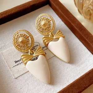Vintage style gold-toned bow earrings with cream heart-shaped drops on a linen jewelry tray