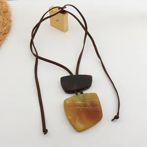 Detail of geometric resin necklace with marbled yellow and brown pendants on leather cord