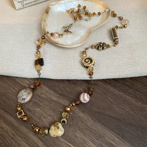 Close-up detail of Bohemian beaded necklace featuring natural shells and vintage metal charms