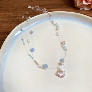 Close-up detail of a multi-layer beaded necklace with blue glass beads and silver shell