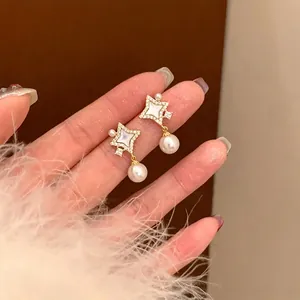 Close-up detail of 14K gold plated star earrings with white pearls and sparkling zircons