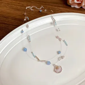 Detailed view of a multi-layered necklace featuring shell pendant, pearls and blue beads.