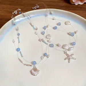Close-up detail of multi-layer seaside vacation necklace featuring silver starfish and shell charms