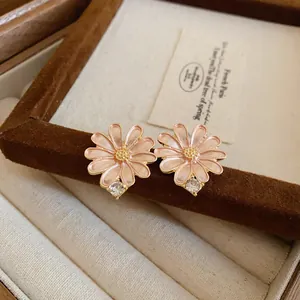 Detailed close-up view of pink enamel daisy earrings resting on a velvet jewelry box