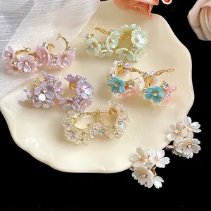 Variety of French style flower stud earrings with rhinestones displayed on a shell plate