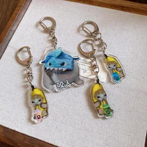 Detailed view of cute Banana Cat and shark cat acrylic keychains on a textured surface