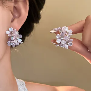 Detail view showing lavender floral stud earrings with shimmering pearlescent petals