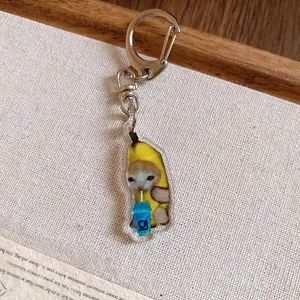 Close-up of a cute acrylic Banana Cat keychain drinking from a blue cup
