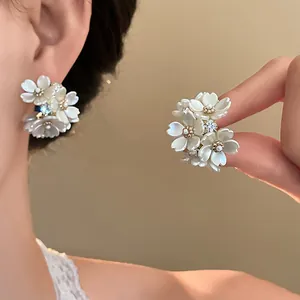 Close-up detail of elegant white floral stud earrings with sparkling rhinestone accents