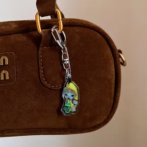 Close-up detail of a cute cartoon banana cat acrylic keychain hanging on a brown bag