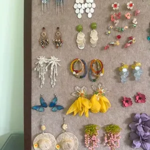 Collection of forest-style butterfly and floral tassel earrings on a felt display board.