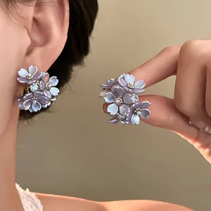 Close-up of elegant floral stud earrings with lavender petals and sparkling rhinestones.