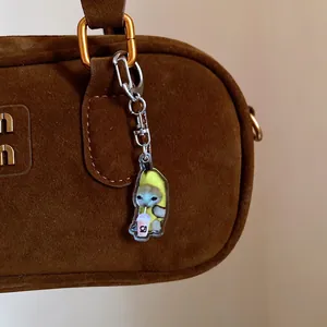 Detailed view of a cute banana cat acrylic keychain charm on a brown suede bag