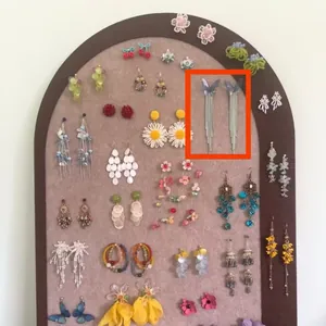 Detailed macro view of iridescent butterfly tassel earrings on a jewelry display board.