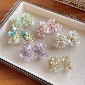 Macro view of various colored floral stud earrings with rhinestones in a display box.