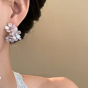 Close-up view of elegant floral earrings with sparkling rhinestones on a model's ear.