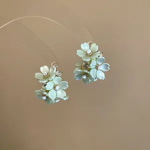 Close-up of elegant pale green flower stud earrings with sparkling crystals