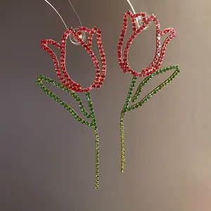 Macro view of floral tulip earrings featuring sparkling red and green rhinestones